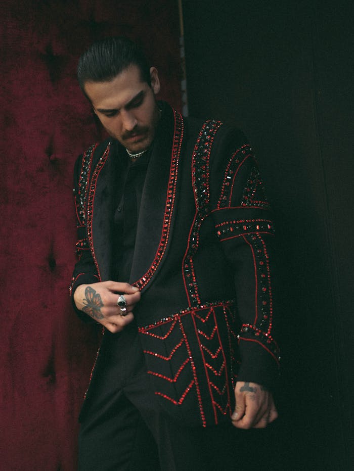 Portrait of a man in ornate black and red jacket, adding a dramatic flair to a moody setting.